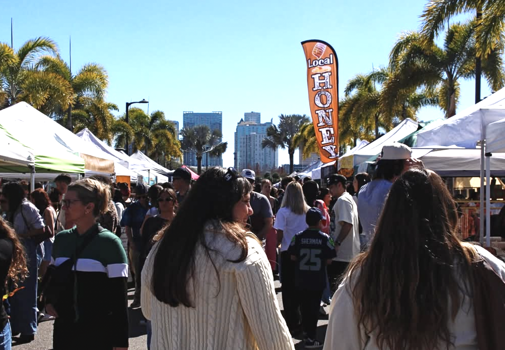 People walking through a busy local market smiling and looking at community makers