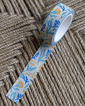 linocut design of blue, gold, and cream organic flowers on decorative washi tape. unrolled showing the design on a textured brown background. by dovetail studio