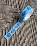 linocut design of florida blue seashells on decorative washi tape. unrolled showing the design on a textured brown background. by dovetail studio