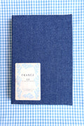Denim textured reading log with a patch labeled 'France' on a blue and white checkered background