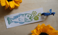 Fish vase with flowers bookmark with ribbon on wood background with sunflowers surrounding it