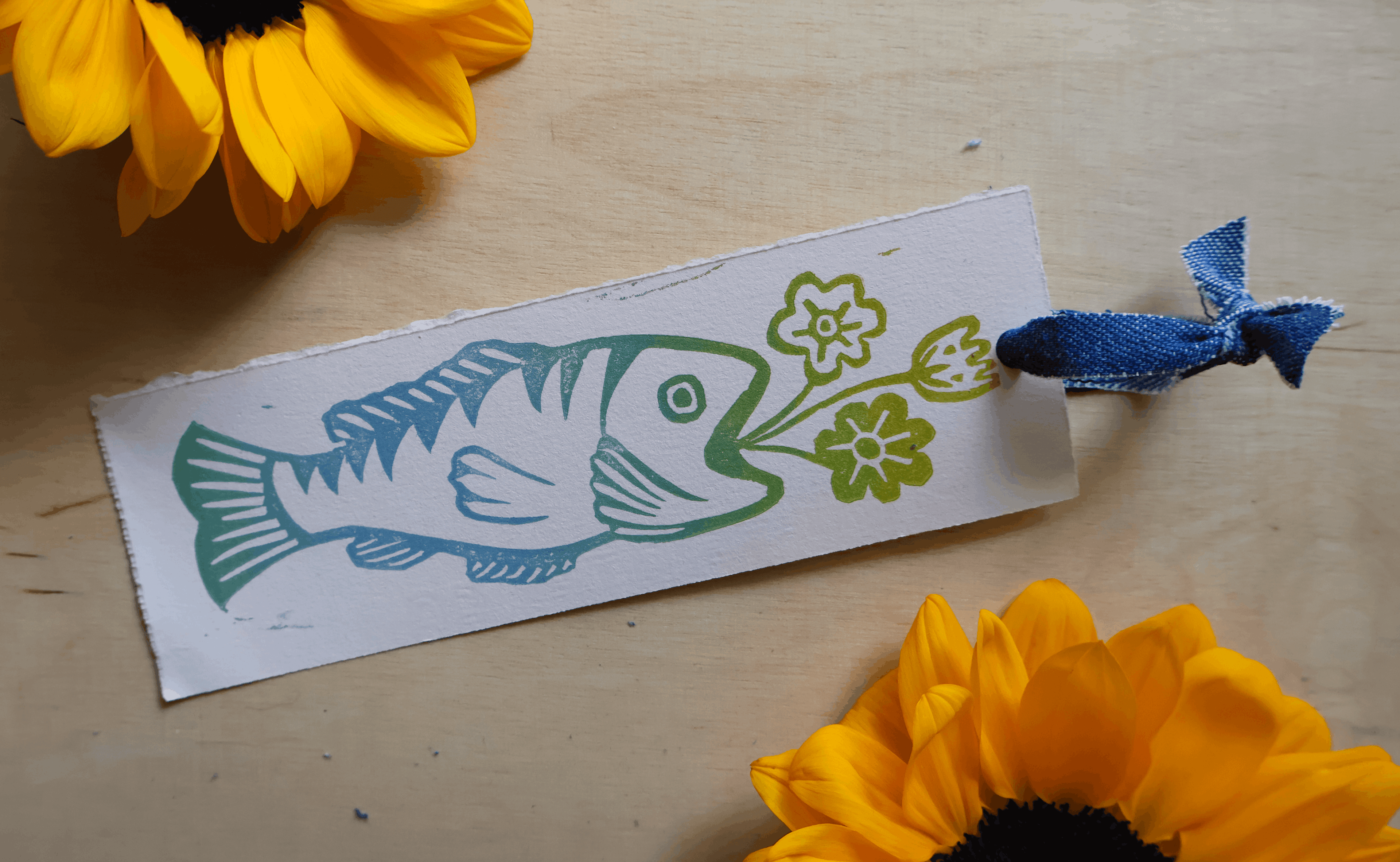 Fish vase with flowers bookmark with ribbon on wood background with sunflowers surrounding it
