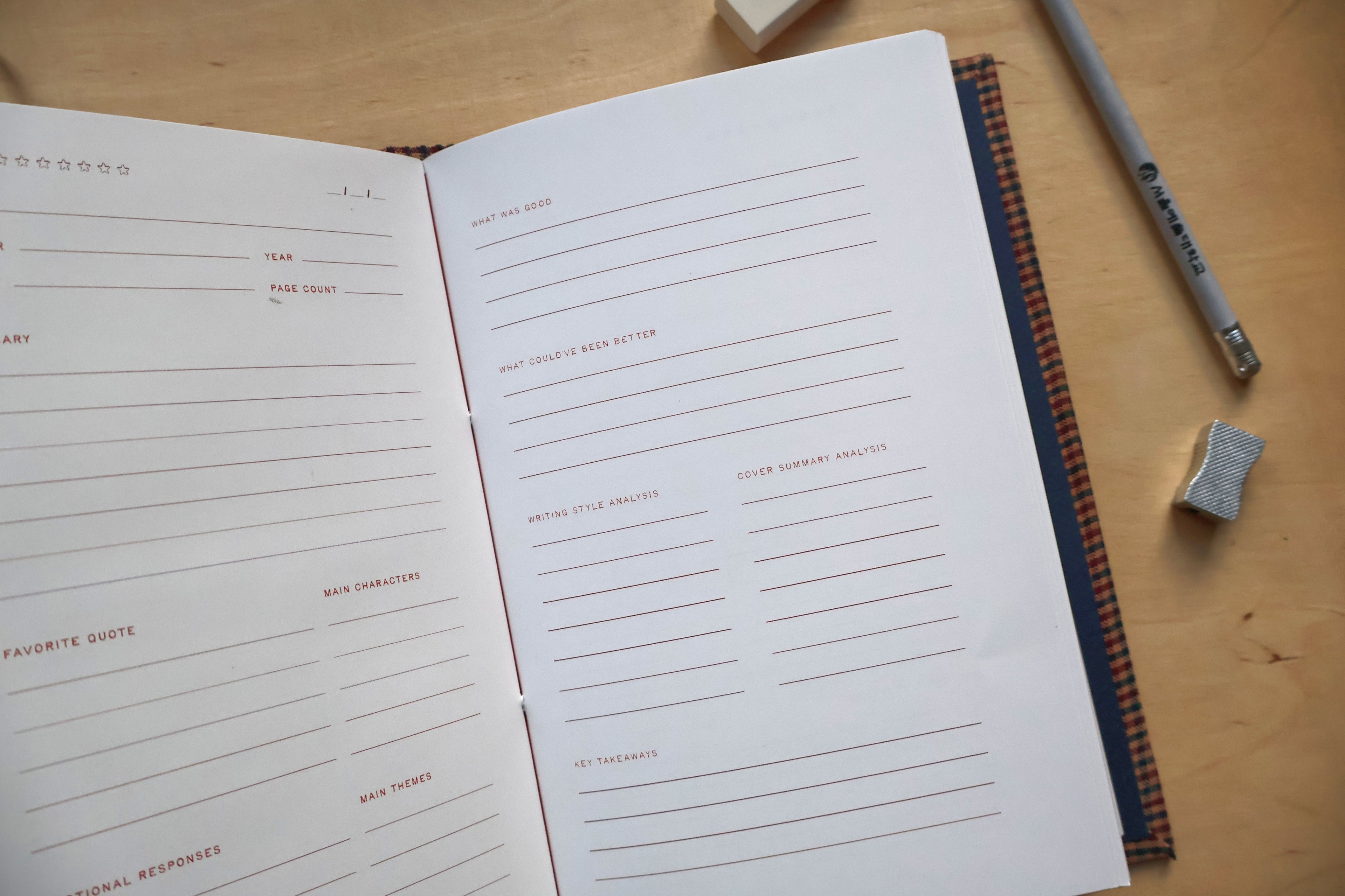 An open reading log on a wooden desk, showing lined pages with prompts and sections for writing and reflection. A pencil and eraser are placed beside it on the wood surface.
