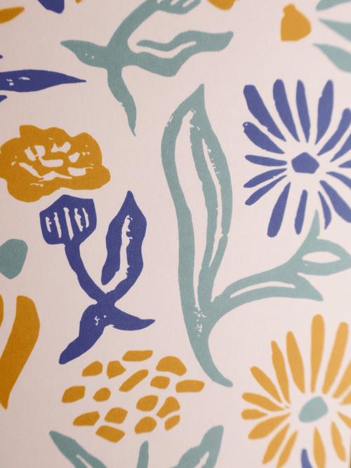 A close-up of a fabric or wallpaper pattern featuring stylized floral and leaf motifs in navy blue, teal, and mustard yellow on a warm off-white background.