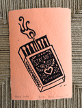 A square peach paper print or card featuring a black line-art illustration of an open matchbox with a hand reaching in and the words “STAY SOFT. BITE BACK.