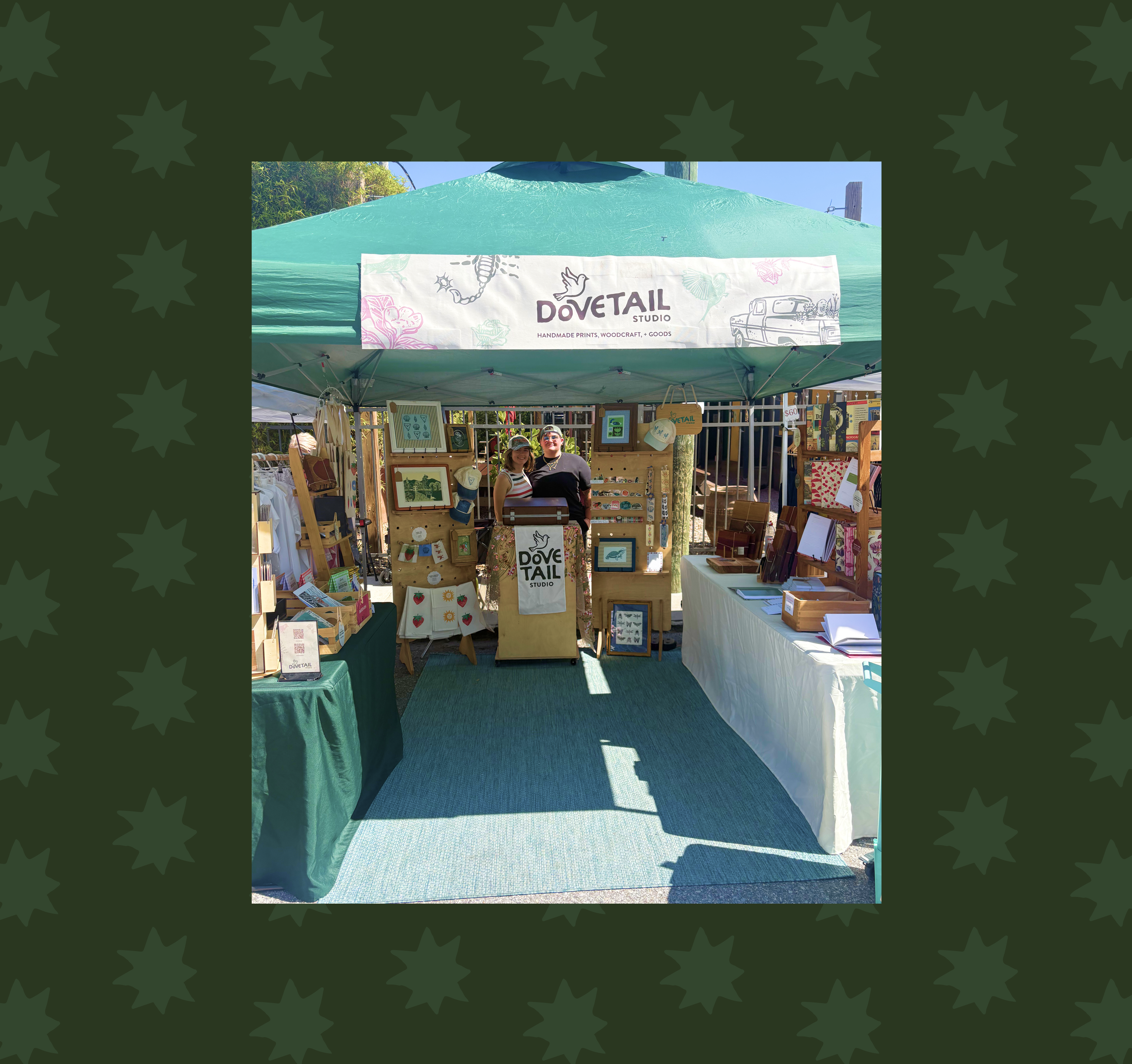 lilli jones and bella thompson, owners of dovetail studio standing in their booth setup in st petersburg florida with handmade linocut prints, hand bound journals, stationery, and home goods