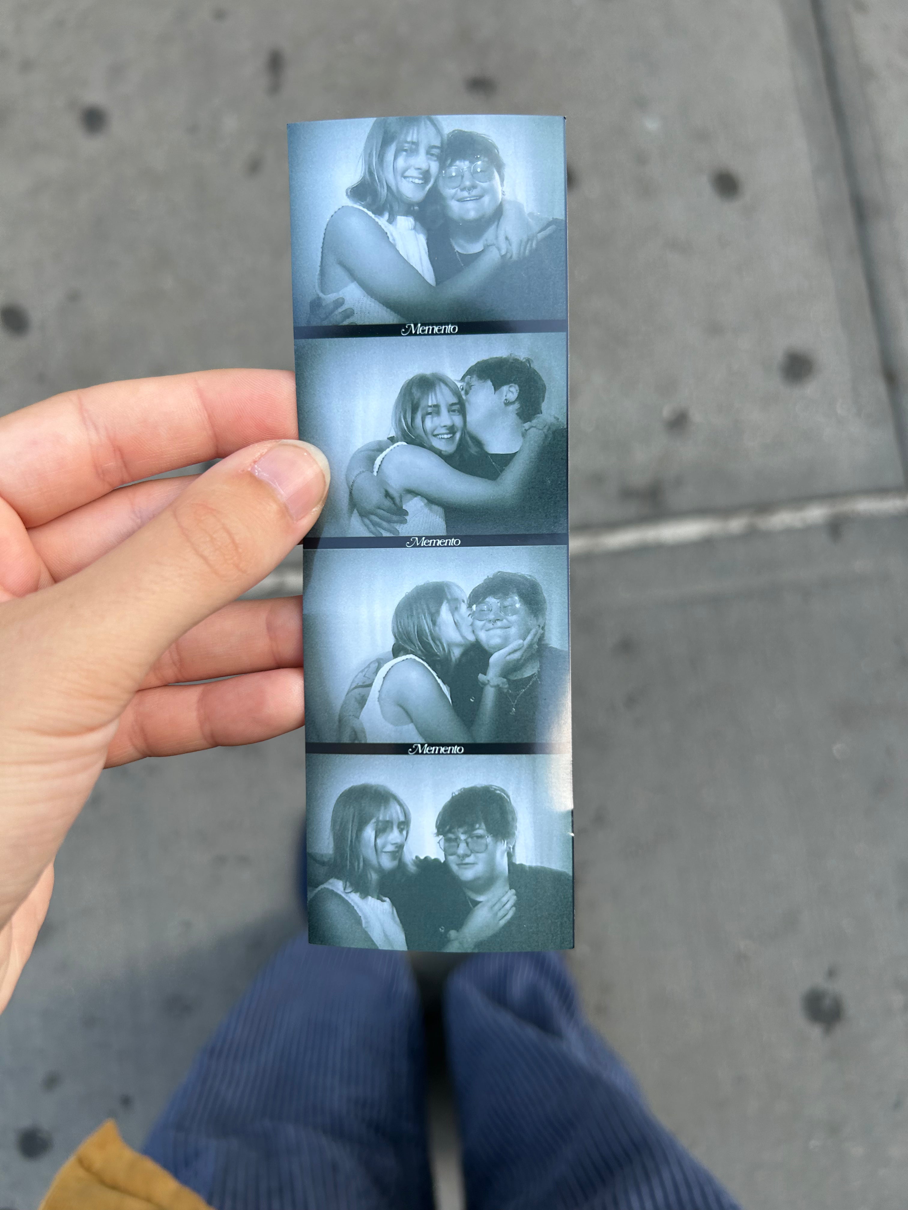 person holding a black and white photobooth image of the dovetail studio owners bella thompson and lilli jones on the sidewalk