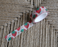 linocut design of red strawberries with gold stars on decorative washi tape. unrolled showing the design on a textured brown background. by dovetail studio