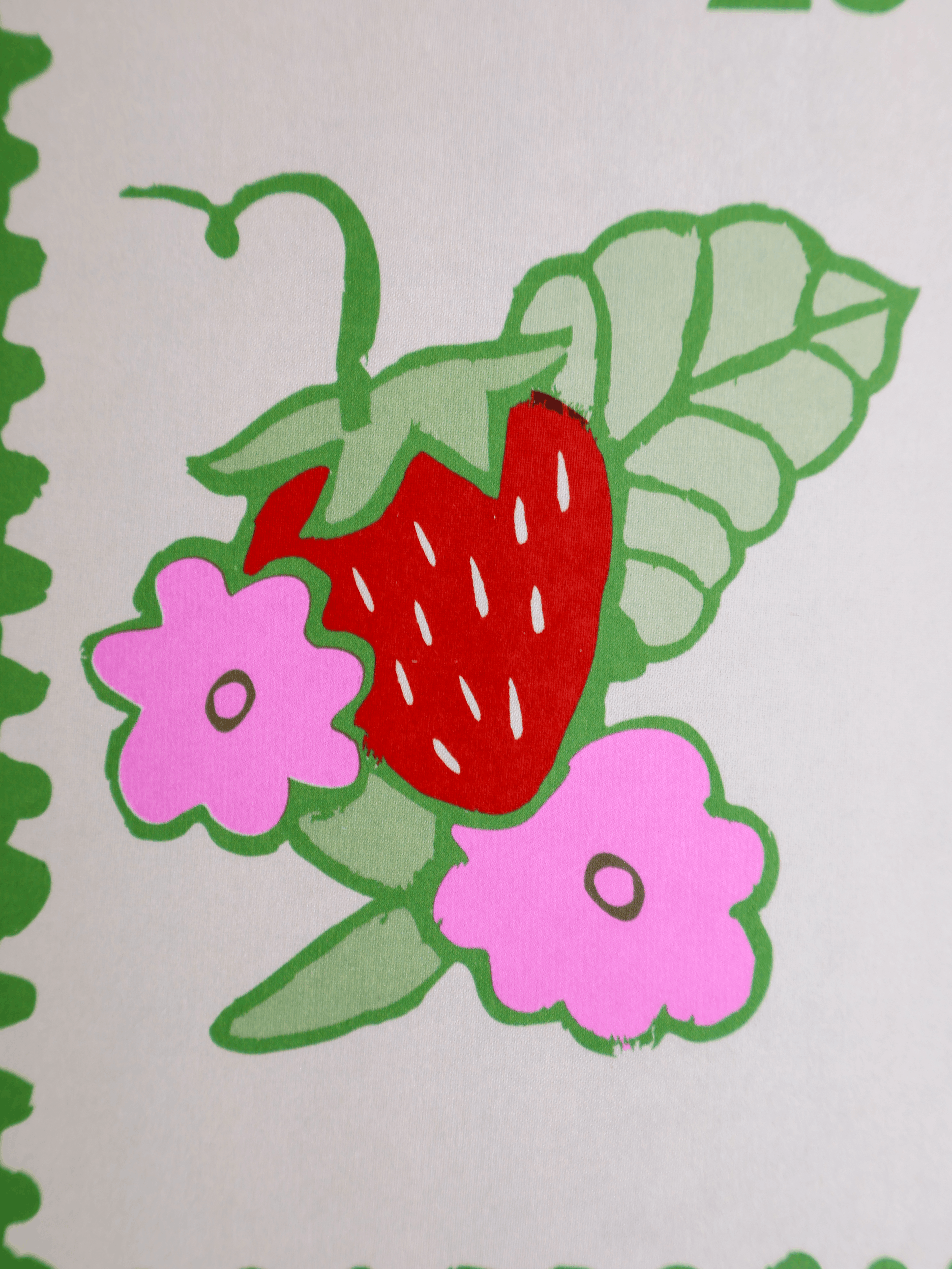 A close-up of a printed strawberry illustration with green leaves, pink flowers, and a red strawberry on a white background.