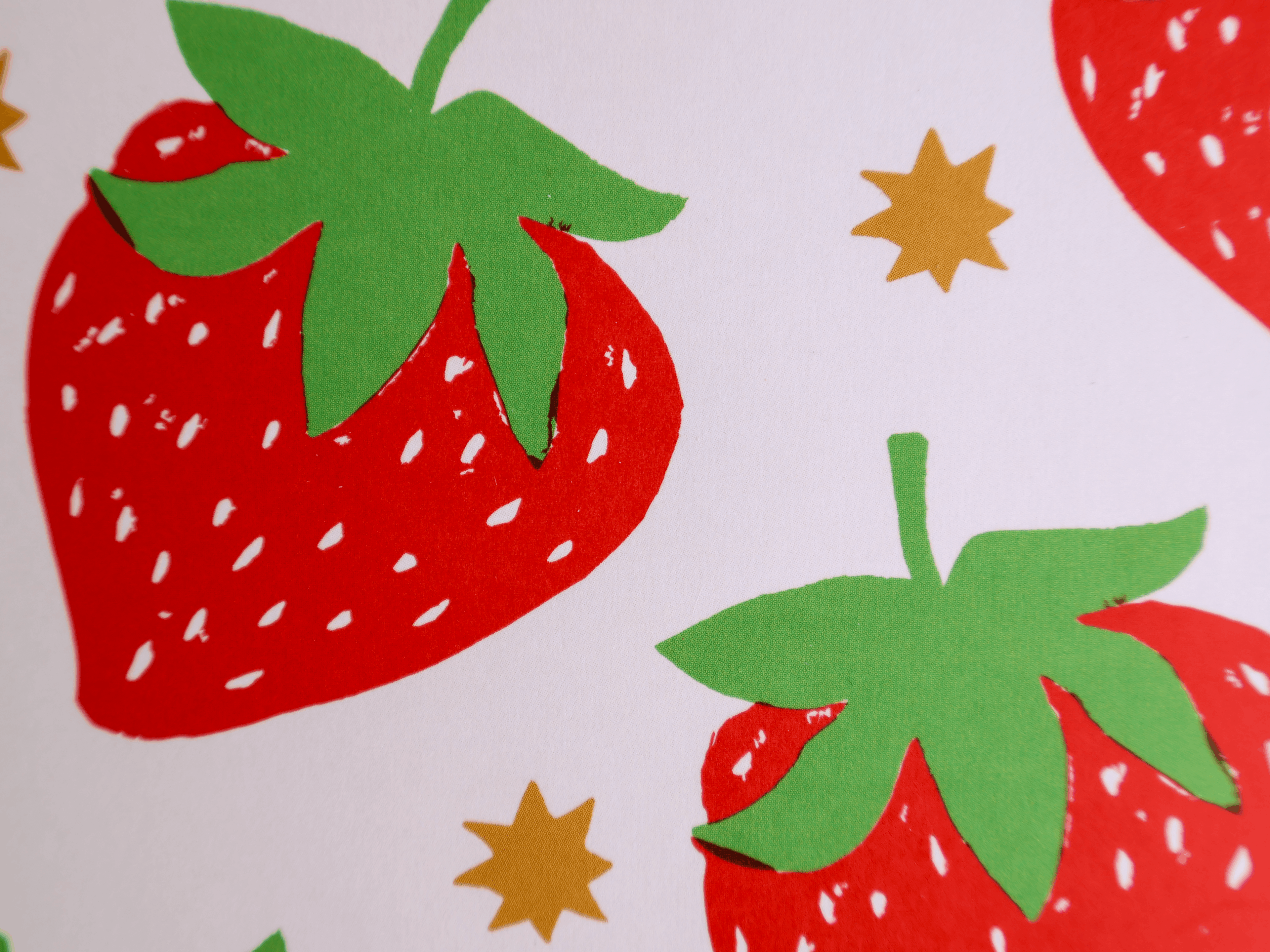 A close-up of a strawberry pattern featuring red strawberries with green leafy tops and small gold star accents on a white background.