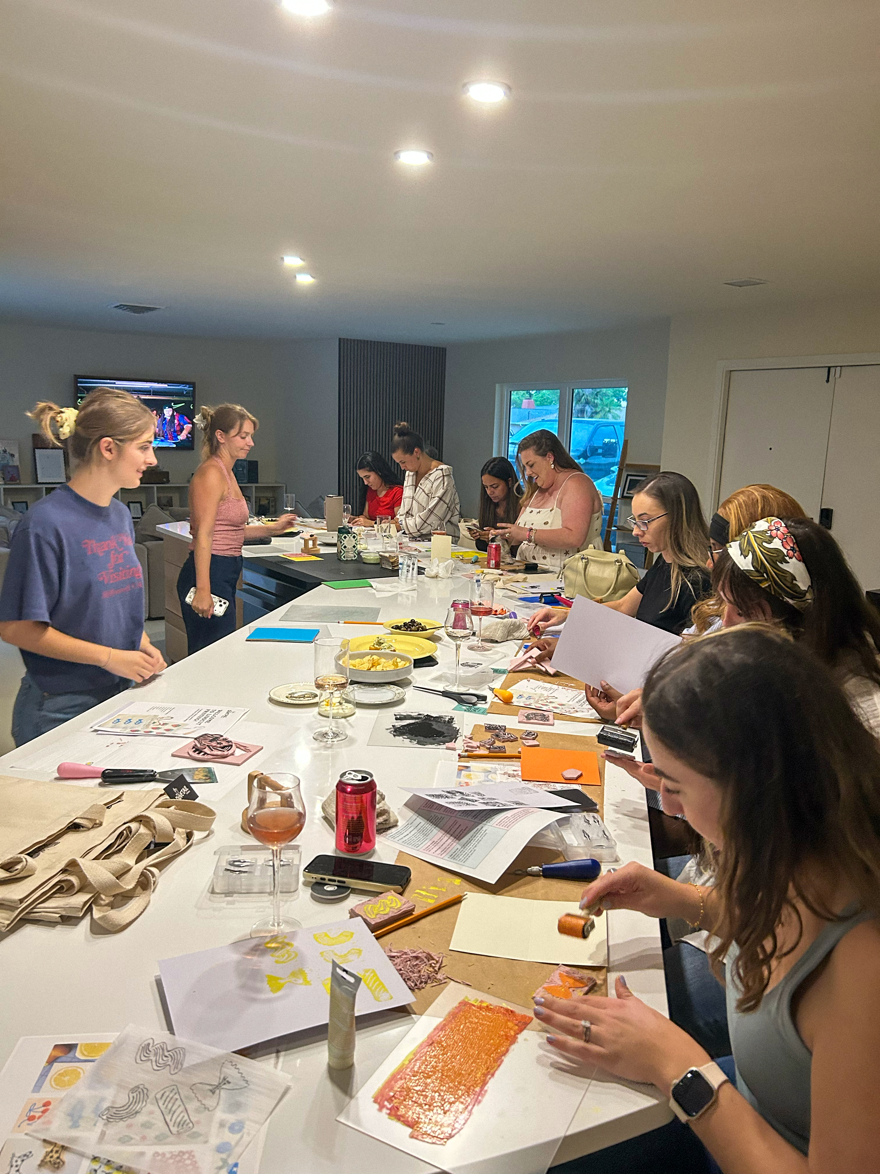 group of 14 people taking a linocut printmaking workshop for totebags and greeting cards actively working  in sarasota florida led by dovetail studio